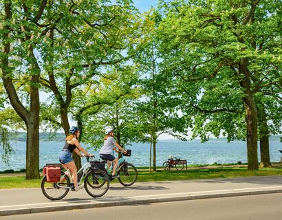 Zwei Frauen fahren auf ihren Fahrrädern entlang der Müritz
