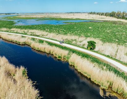 Zwei Fahrradfahrer fahren entlang des Wassers in Bugewitz, gezeigt aus der Vogelperspektive