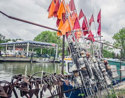 Rote Fischerfahnen und Anker am Hafen von Altwarp mit Booten im Hintergrund