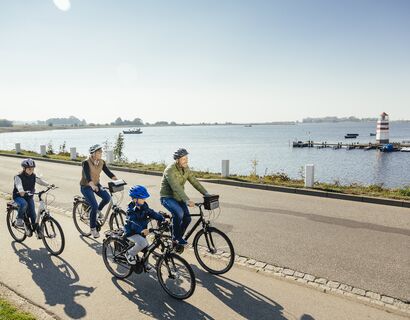 Eine Familie fährt mit dem Fahrrad am Hafen Ummanz entlang