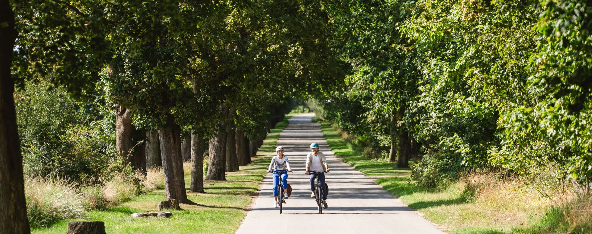Loissin Zwei Fahrradfahrer auf einer Allee von vorne.